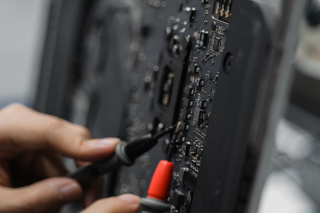 A technician uses tools to repair a circuit board, focusing on microelements.